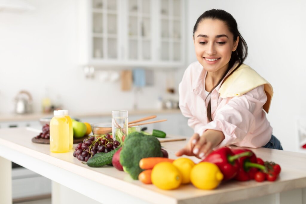 mulher sorrindo pegando fruta em bancada em cozinha