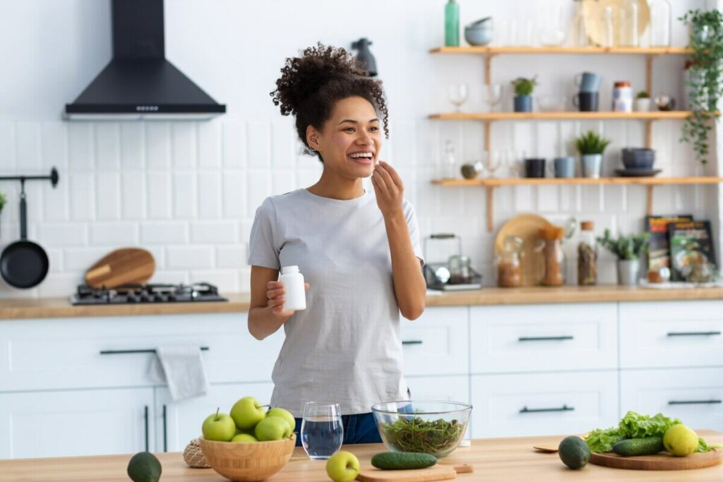 mulher tomando suplemento sorrindo em cozinha