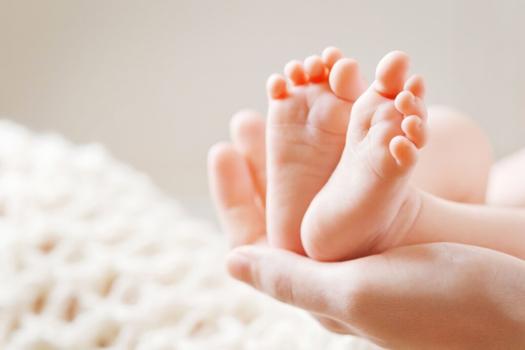 Mãos segurando os dois pezinhos de um bebe recém nascido