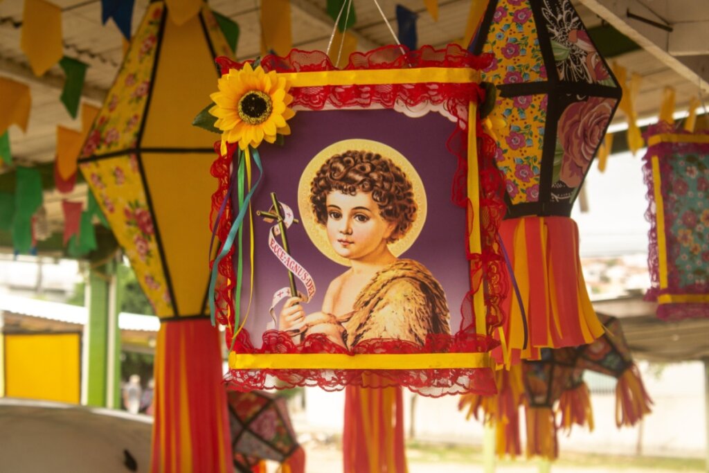 Bandeira com imagem de São João em frente a balões de festa junina