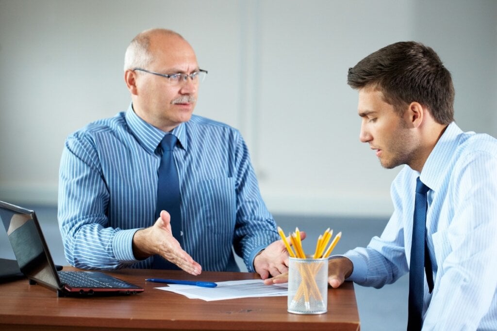 Dois homens sentado em um escritório conversando 