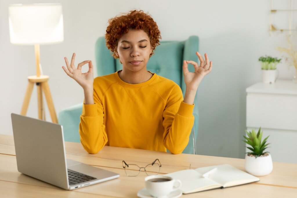 Mulher sentada meditando em frente a um notebook