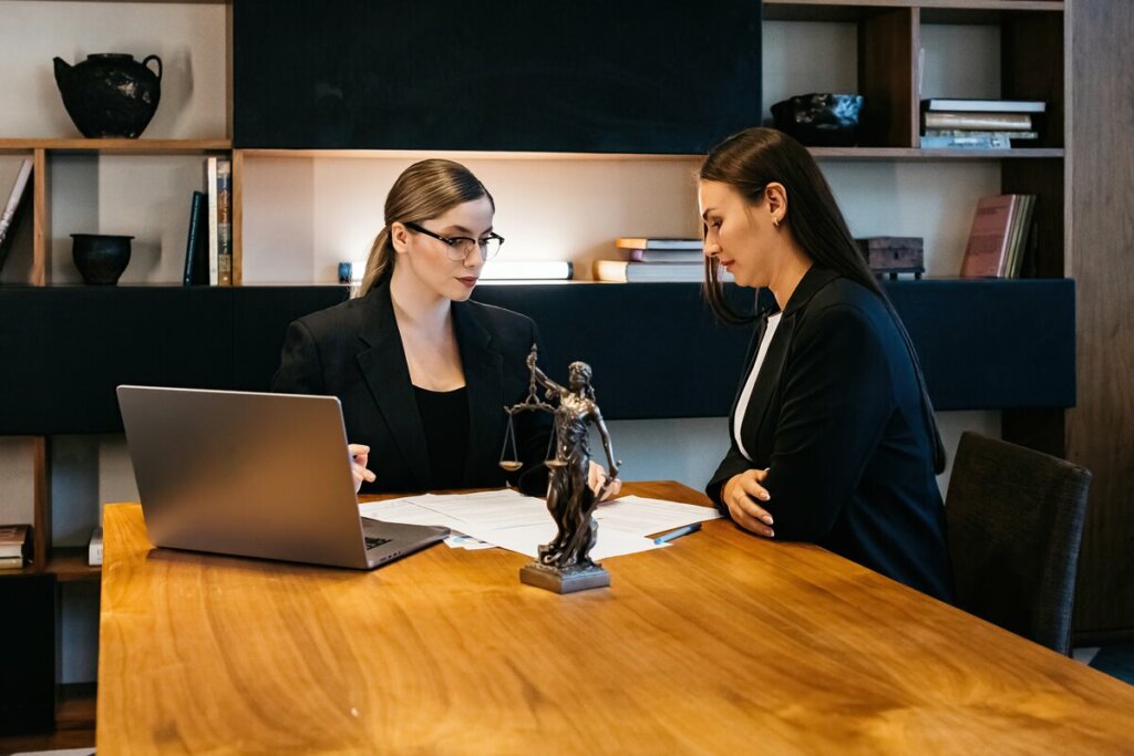 Duas mulheres sentadas em uma mesa de reuniões