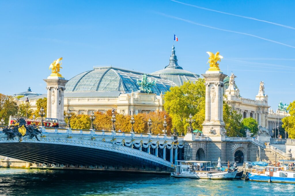 Vista do Grand Palais com céu azul e uma ponte