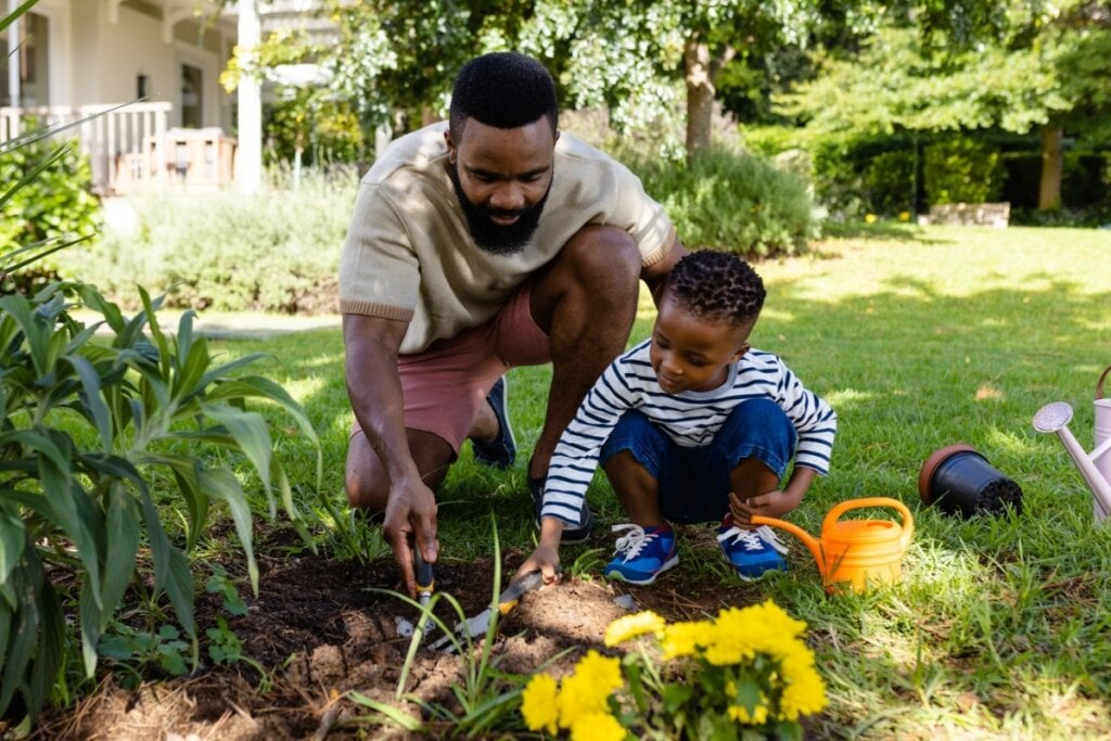 Homem e menino plantando flores em um jardim 