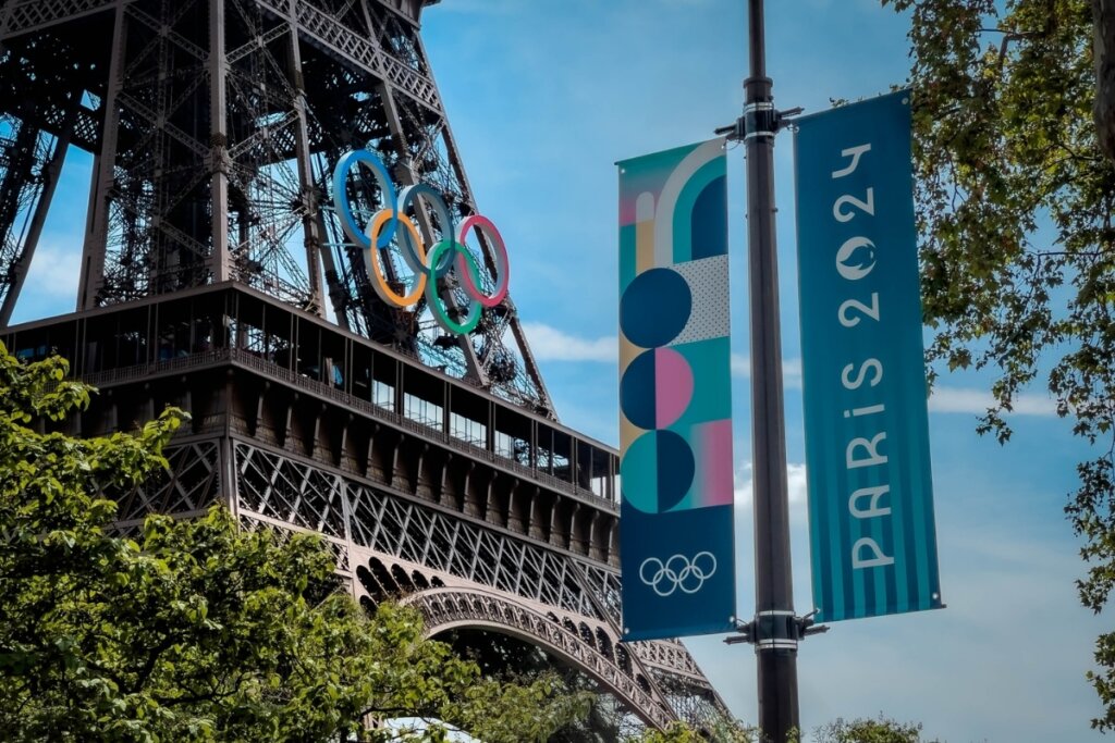 Vista de uma placa das Olimpíadas de Paris 2024 em frente a Torre Eiffel