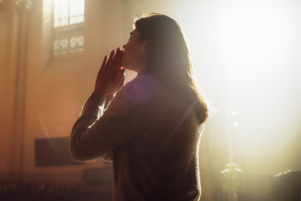Mulher ajoelhada em uma igreja orando 