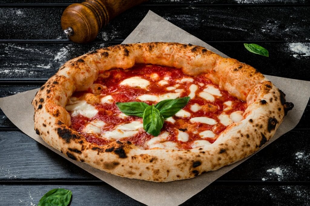 Pizza com molho de tomate, queijo e manjericão em papel branco