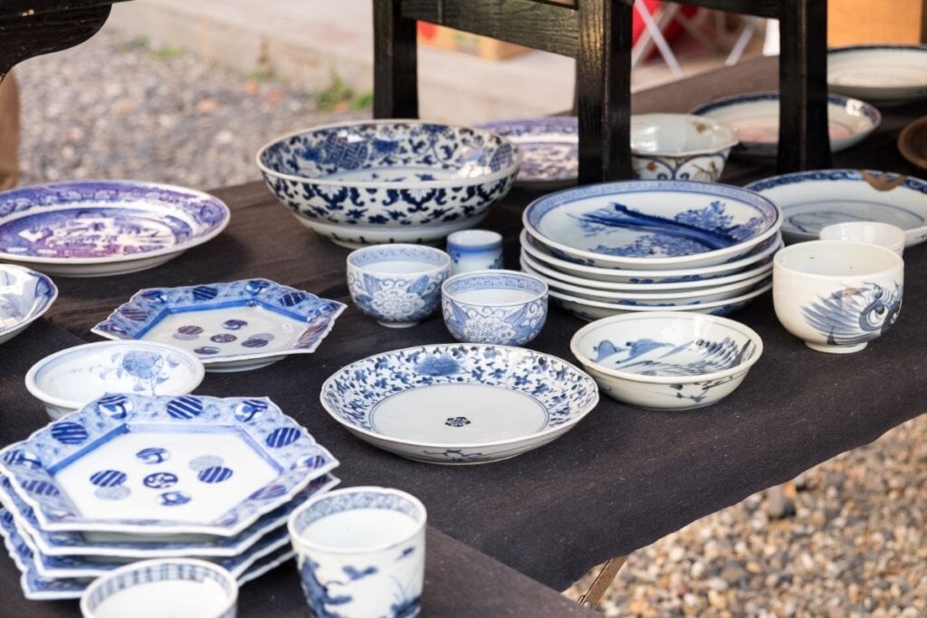 Pratos e xícaras de porcelana brancos com detalhes em azul em cima de uma mesa de madeira 
