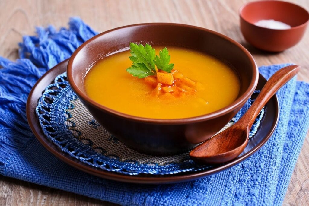 Sopa de cenoura decorada com pedaços de cenoura e coentro