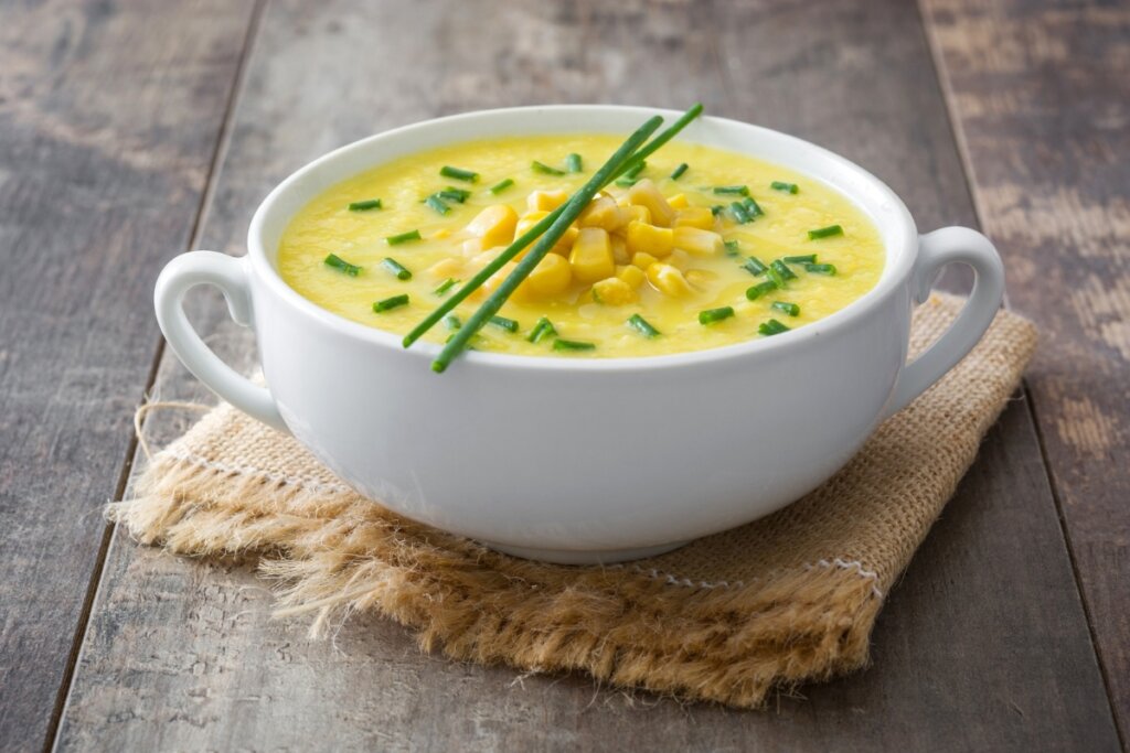 Panela de porcelana com sopa de milho salpicada com salsinha