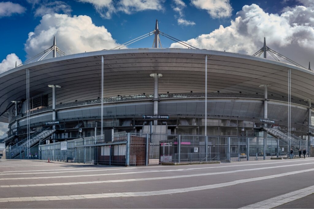 Vista da parte da frente do Stade de France com céu azul com nuvens em cima 