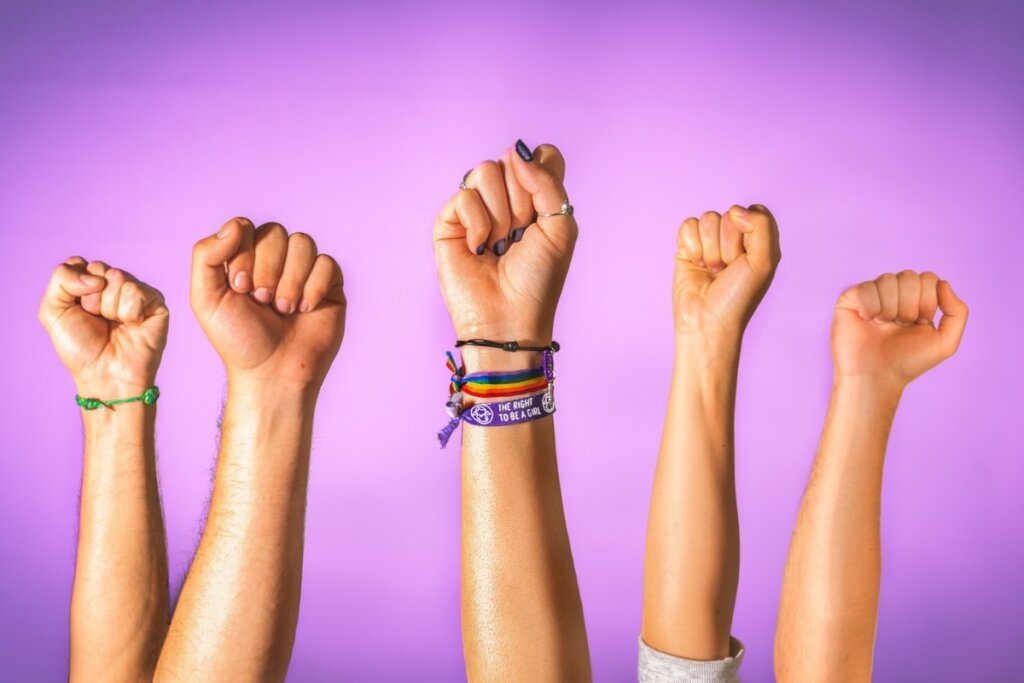 Mãos femininas fechadas em um punho em frente a um fundo roxo