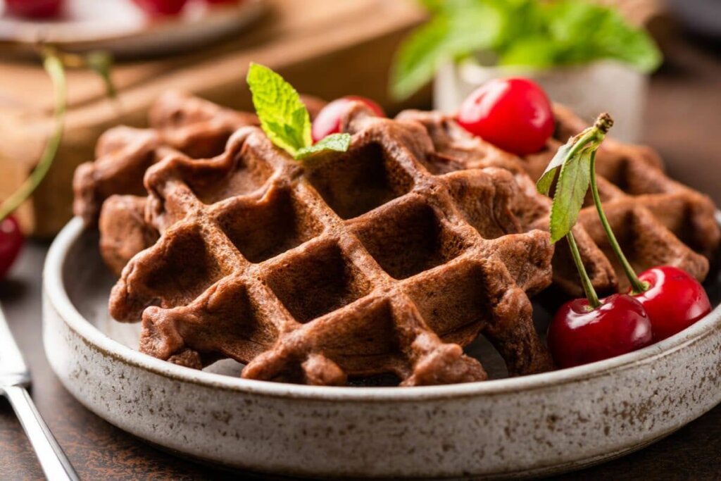 Waffle de chocolate em um recipiente branco decorado com cerejas