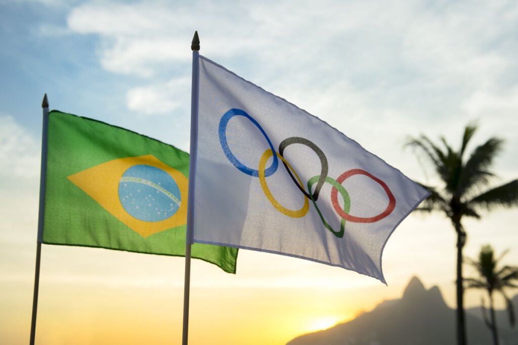 Brandeira do Brasil e das Olimpíadas com céu azul ao fundo