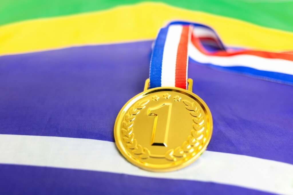 medalha de ouro com número um em cima da bandeira do Brasil