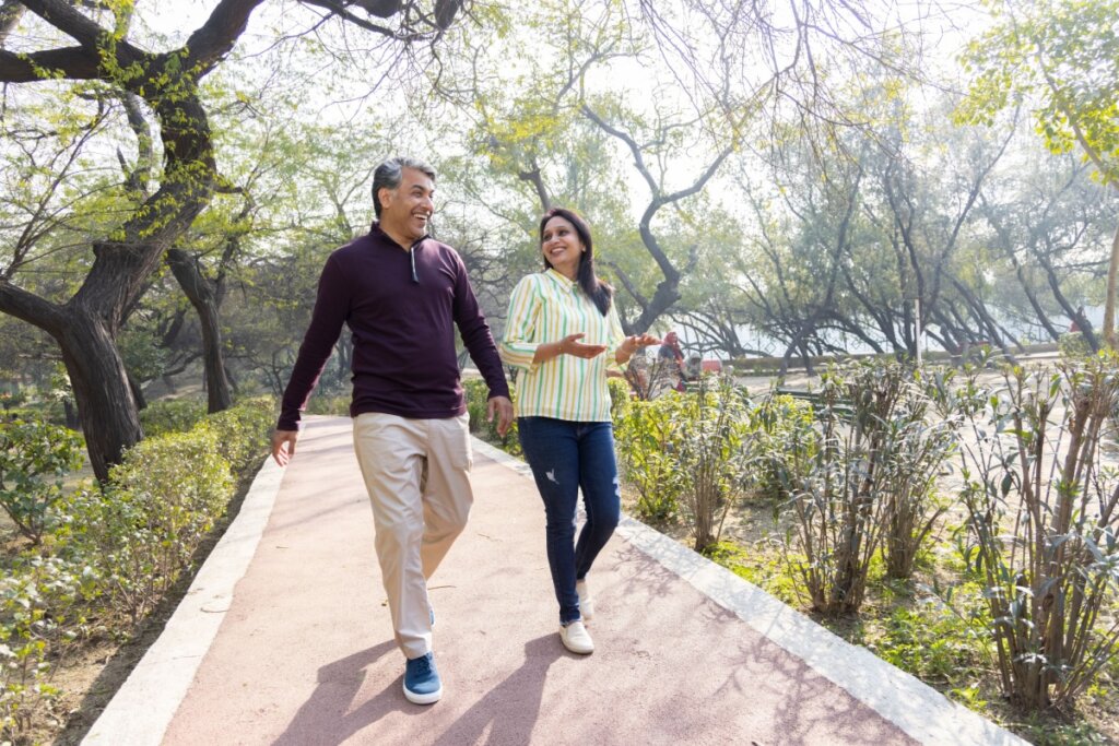 Homem e mulher sorrindo e caminhando em parque