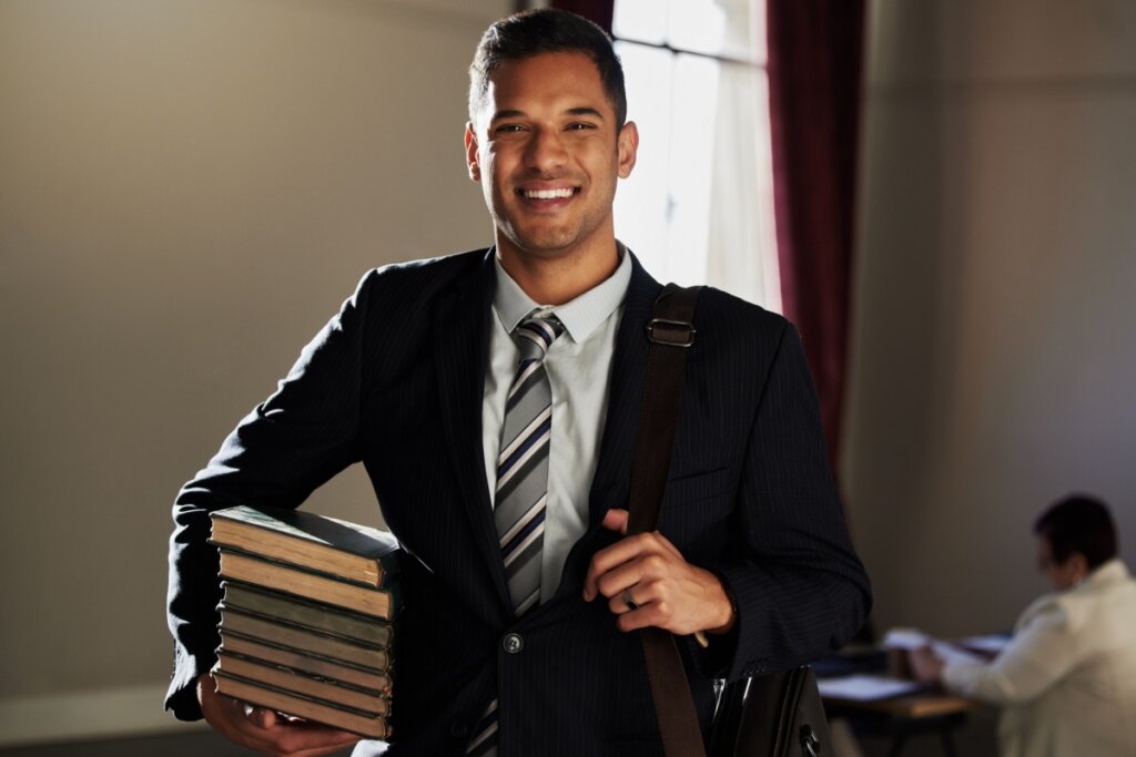 estudante de direito sorrindo segurando vários livros no braço