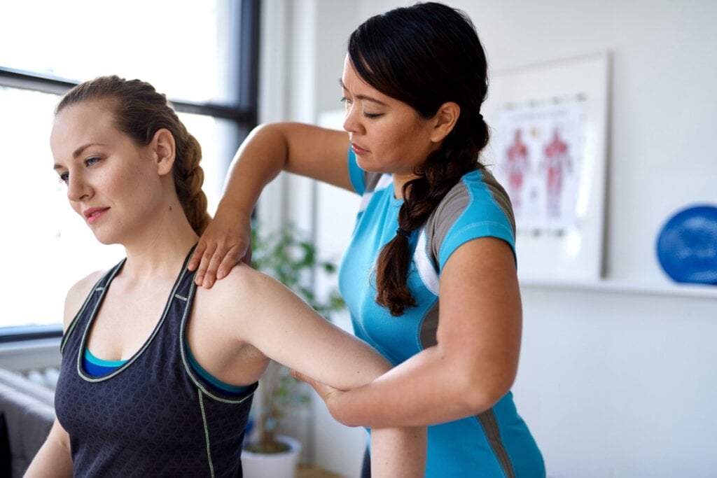 Fisioterapeuta examinando o ombro de mulher em consultório