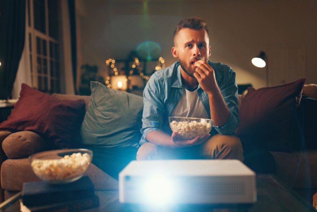 Homem vendo TV enquanto come pipoca