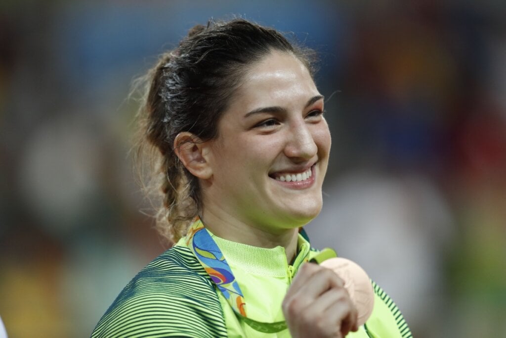 Judoca Mayra Aguiar sorrindo com medalha em mãos