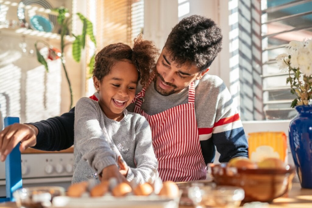 Pai e menina na cozinha sorrindo e bandeja com ovos á frente