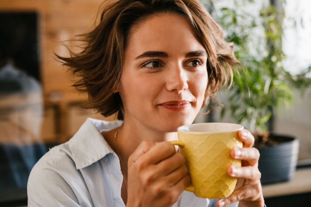 Mulher tomando chá com uma expressão tranquila 
