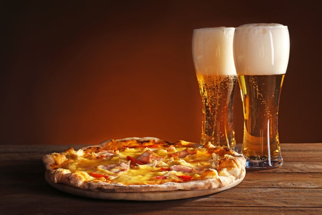 Pizza e cerveja em cima de uma mesa de madeira