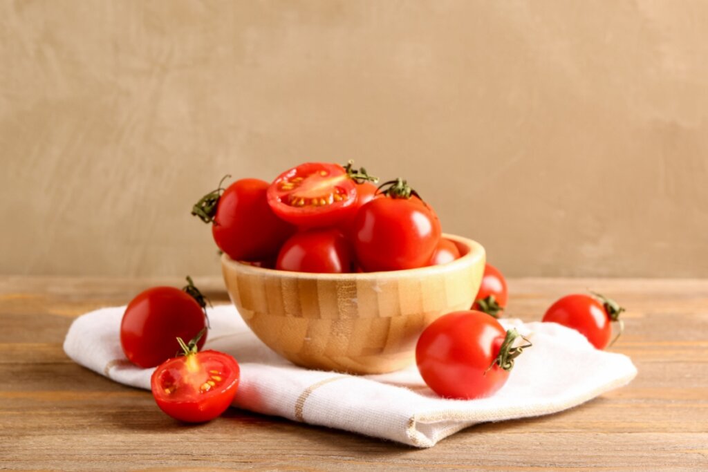 Cumbuca com tomates em cima de uma mesa de madeira