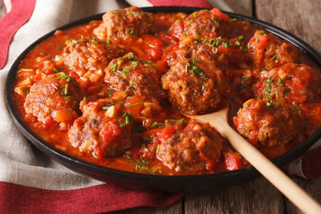 Almôndegas com molho de tomate em recipiente em cima de pano branco e vermelho