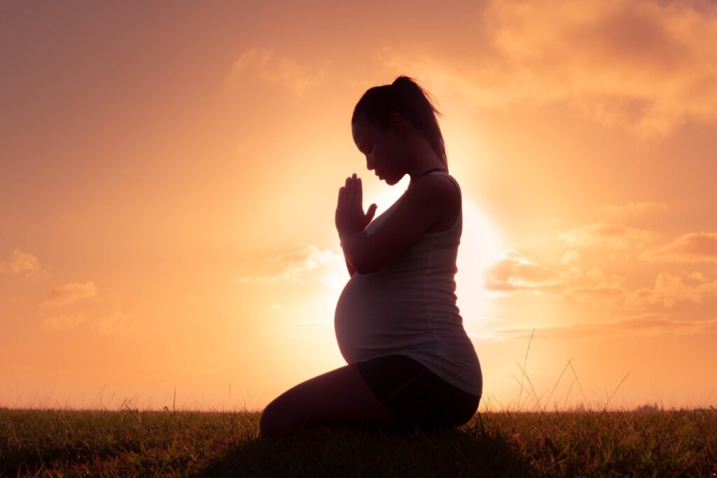 Mulher meditando em frente ao pôr do sol 