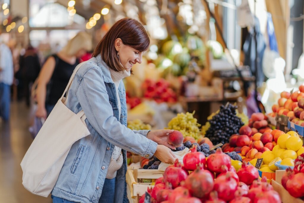 Mulher em uma feira escolhendo frutas