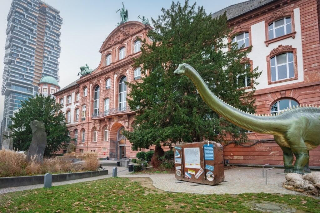 Imagem da fachada de Museu senckenberg com a estátua de um dinossauro 