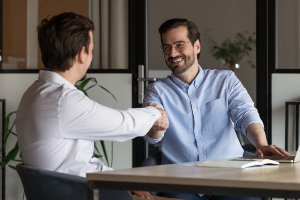 Dois homens sentados dando a mão em comprimento