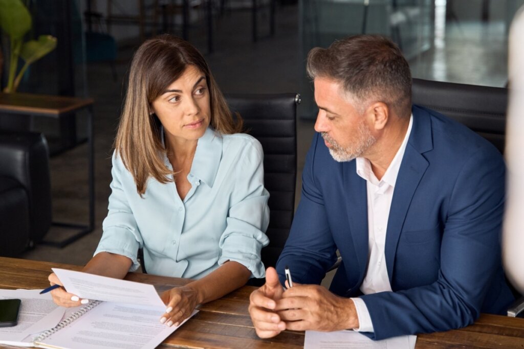 Homem e mulher sentados em uma sala de reunião conversando