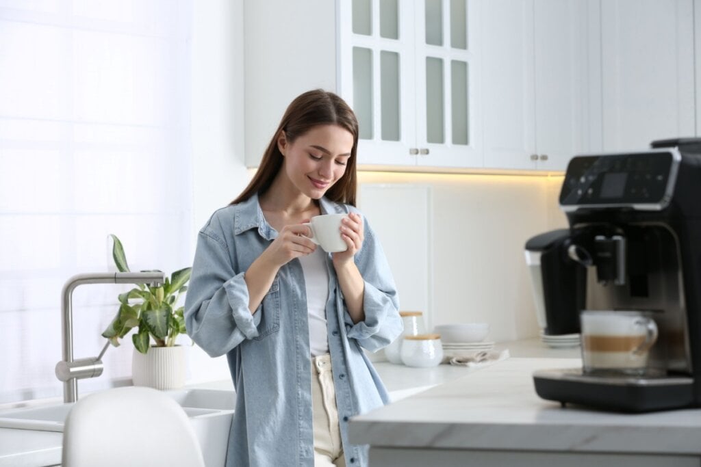 Mulher bebendo café na cozinha 