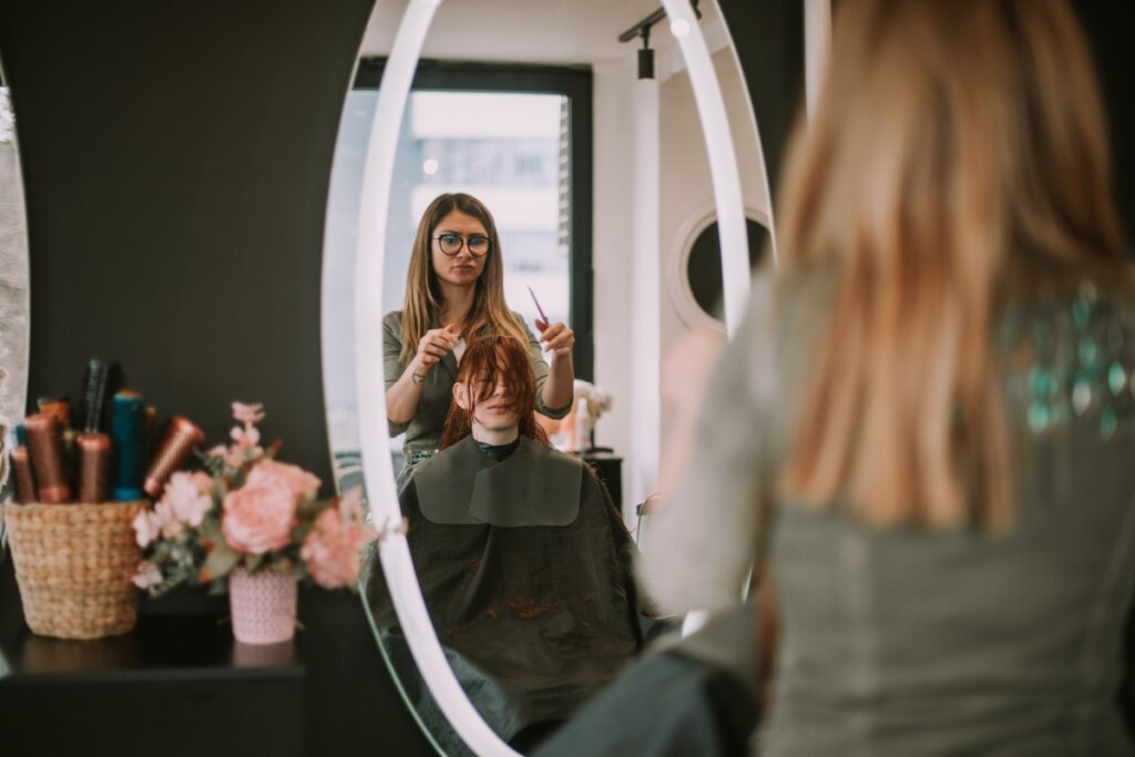 Cabeleireira prestes a cortar franja de mulher ruiva