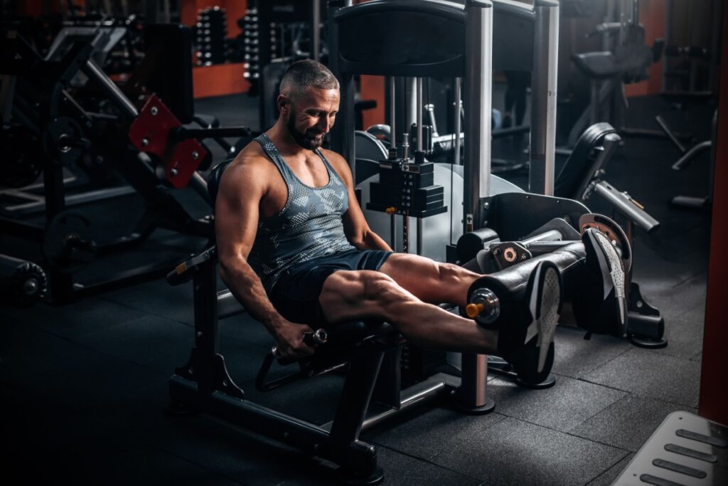 Homem fazendo exercício na cadeira extensora na academia