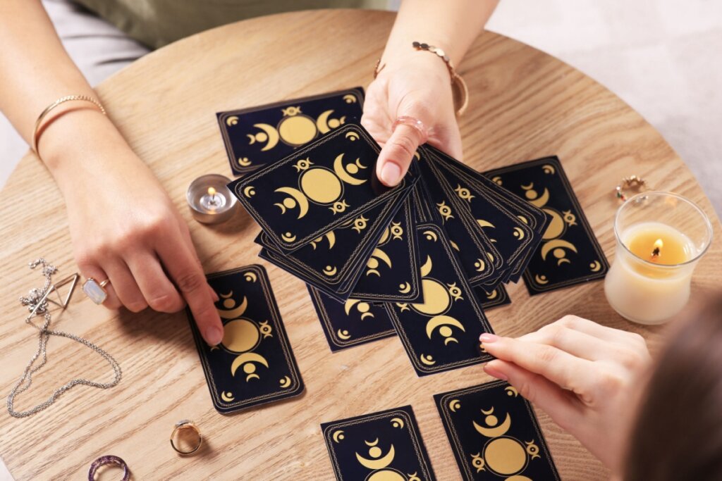 mãos femininas segurando cartas pretas de tarot