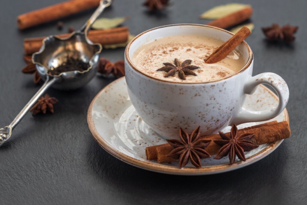 Chai latte em caneca de cerâmica com canela e anis-estrelado no pires