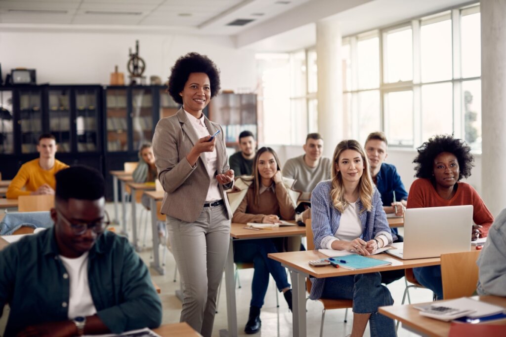 classe de estudantes adultos e professora em pé sorrindo