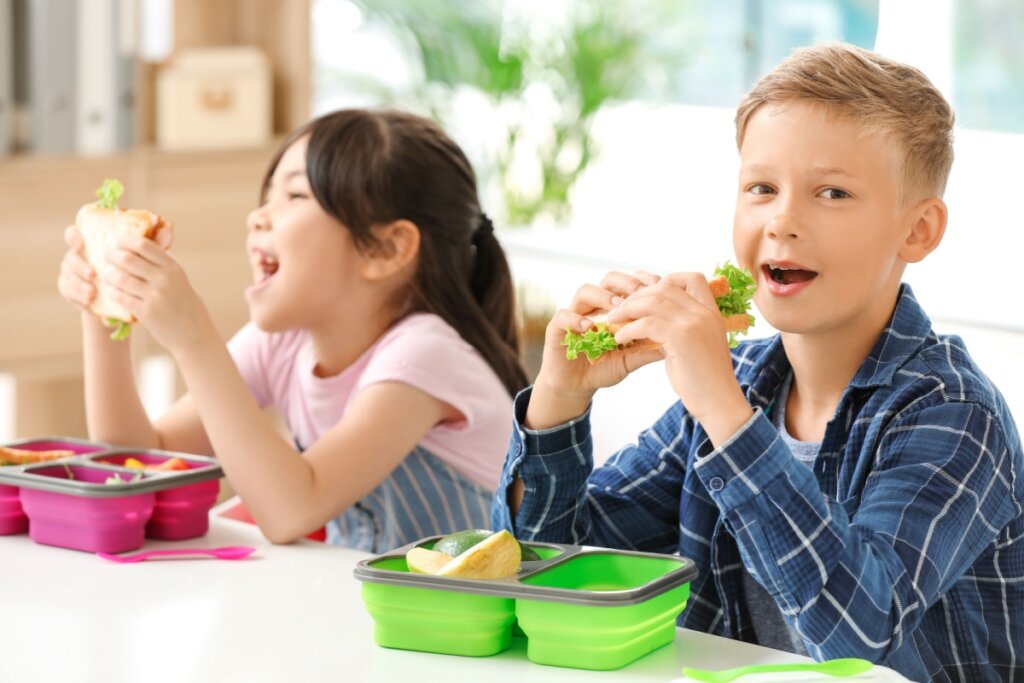 duas crianças comendo lanche em lancheira