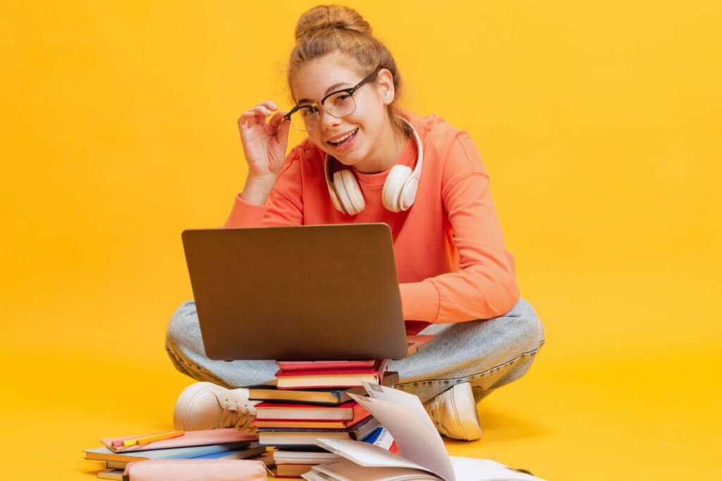 estudante com notebook e livros sorrindo em um plano de fundo amarelo