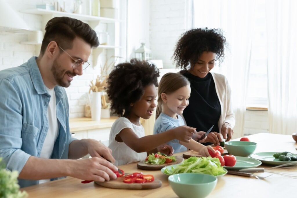 Família cozinhando junta, os pais e duas filhas