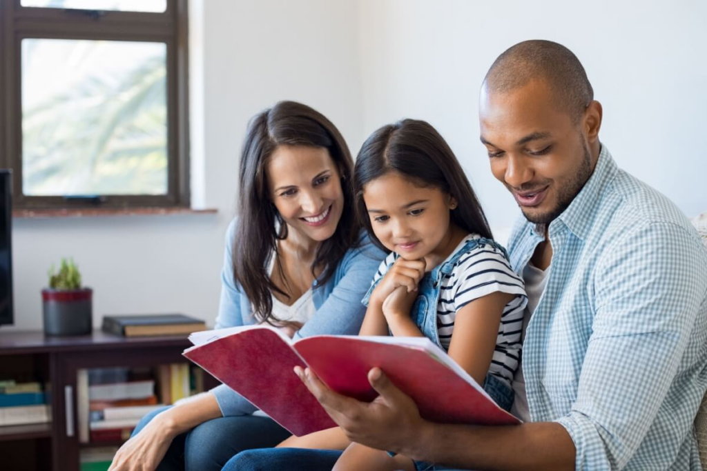 homem e mulher lendo livro para menina em uma sala