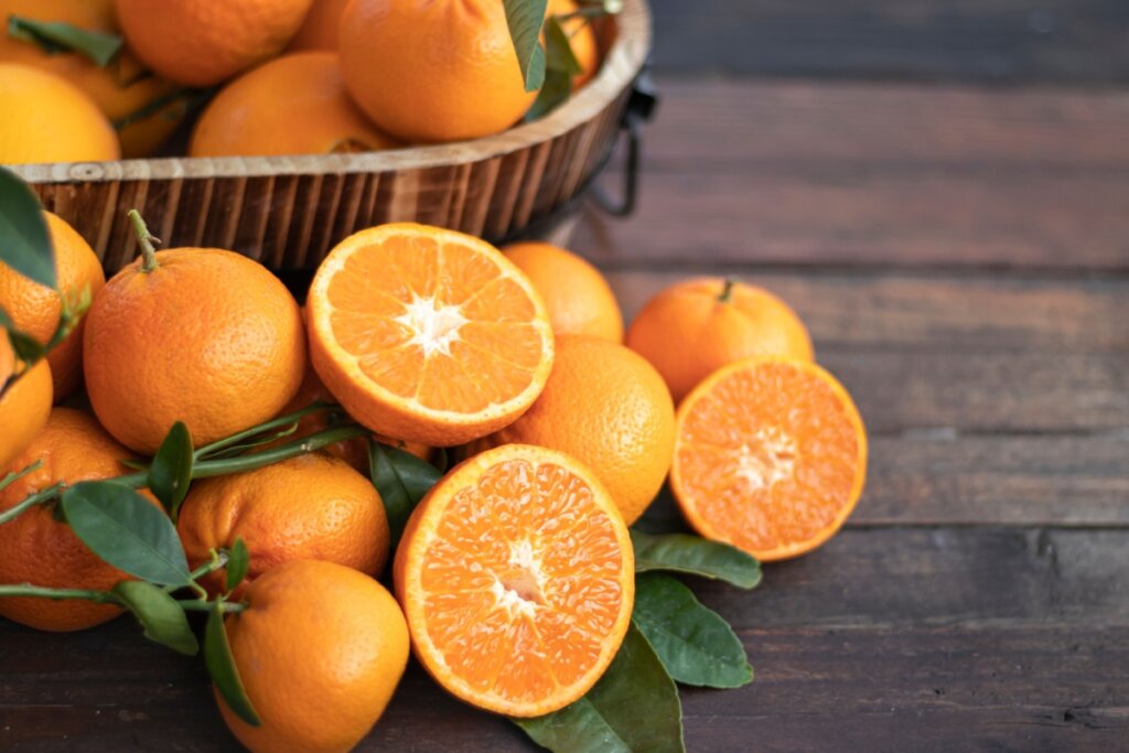 Laranjas em uma mesa de madeira e dentro de um cesto