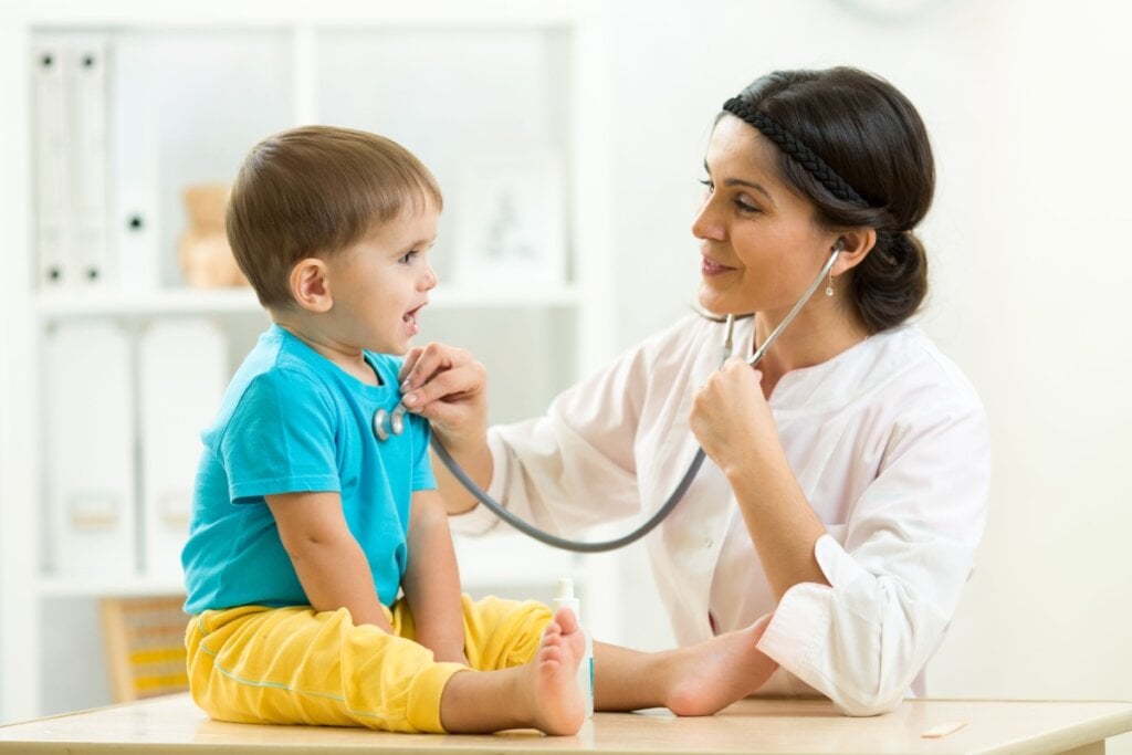 Médica avaliando criança com estetoscópio em cima de uma bancada