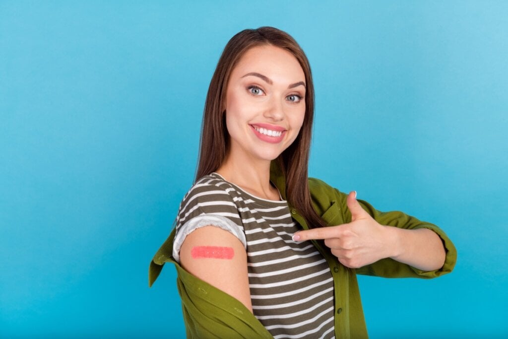 mulher apontando para braço com bandaid