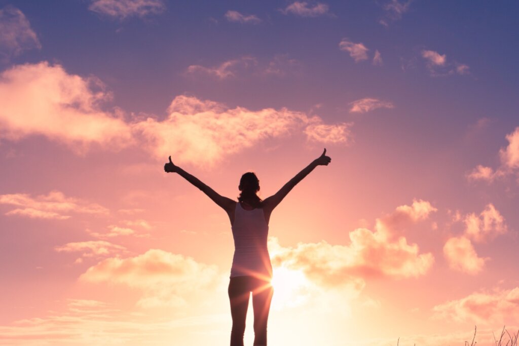 Mulher de costas feliz em por do sol