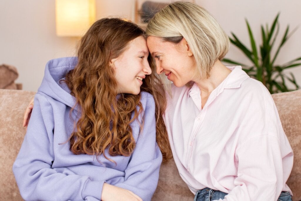 Mulher e adolescente se abraçando no sofá